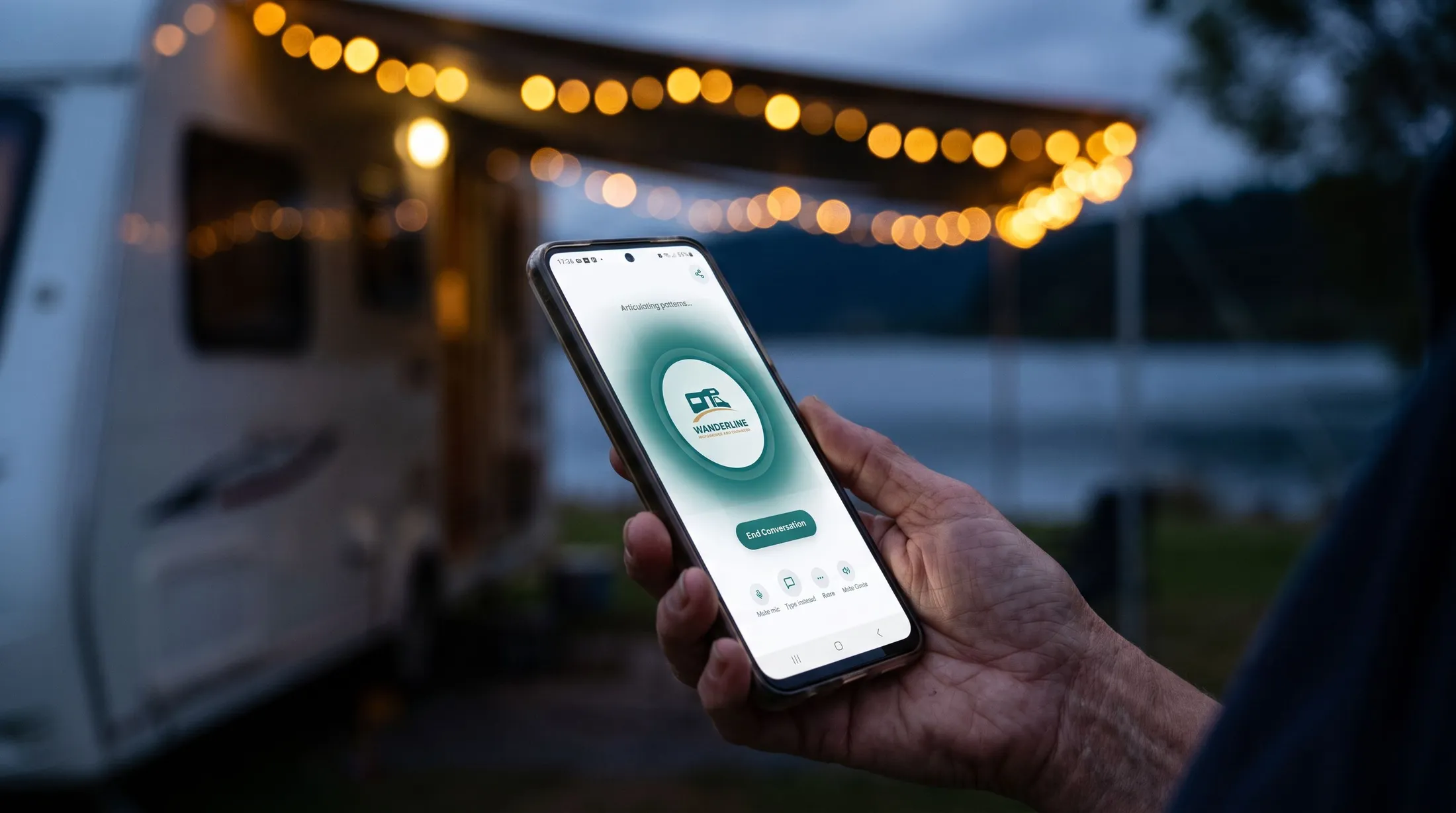 Motorhome owner talking to the Wanderline genie on their phone at dusk, under the awning lights